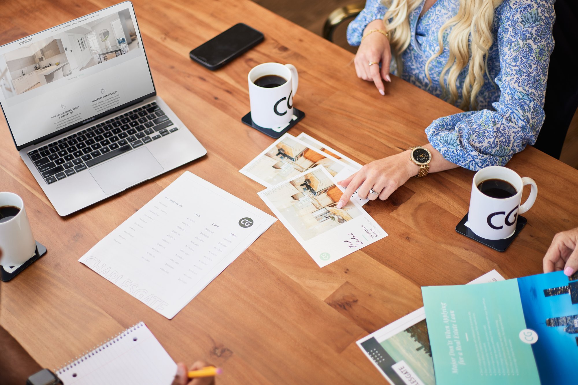 CHARLESGATE marketing collateral on table with laptop and cups of coffee